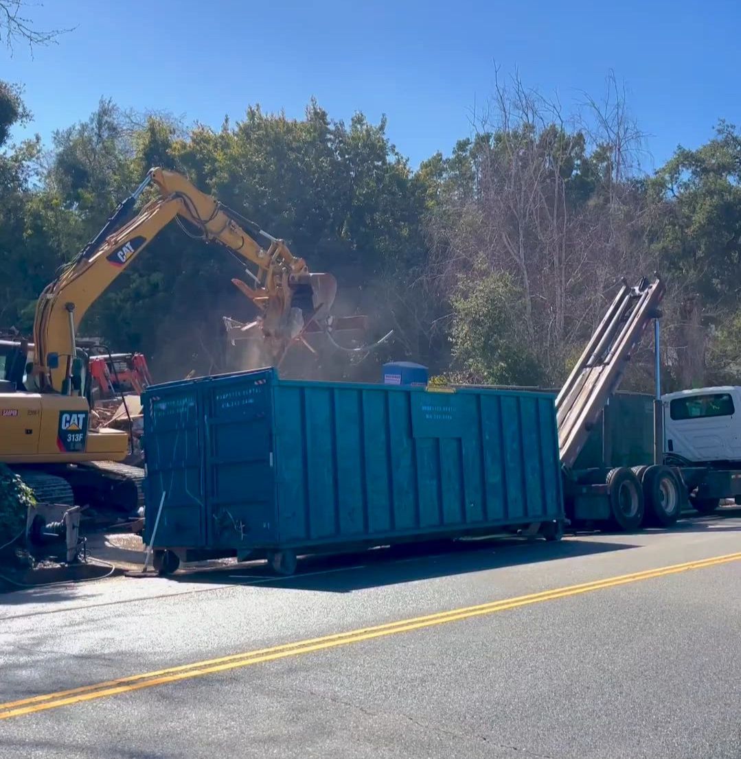 Roll-off dumpsters for rent lined up at a waste service yard.