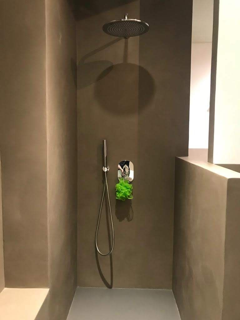 Box doccia moderno con soffione a pioggia, doccetta a mano e nicchia a muro per riporre prodotti da bagno di colore verde.
