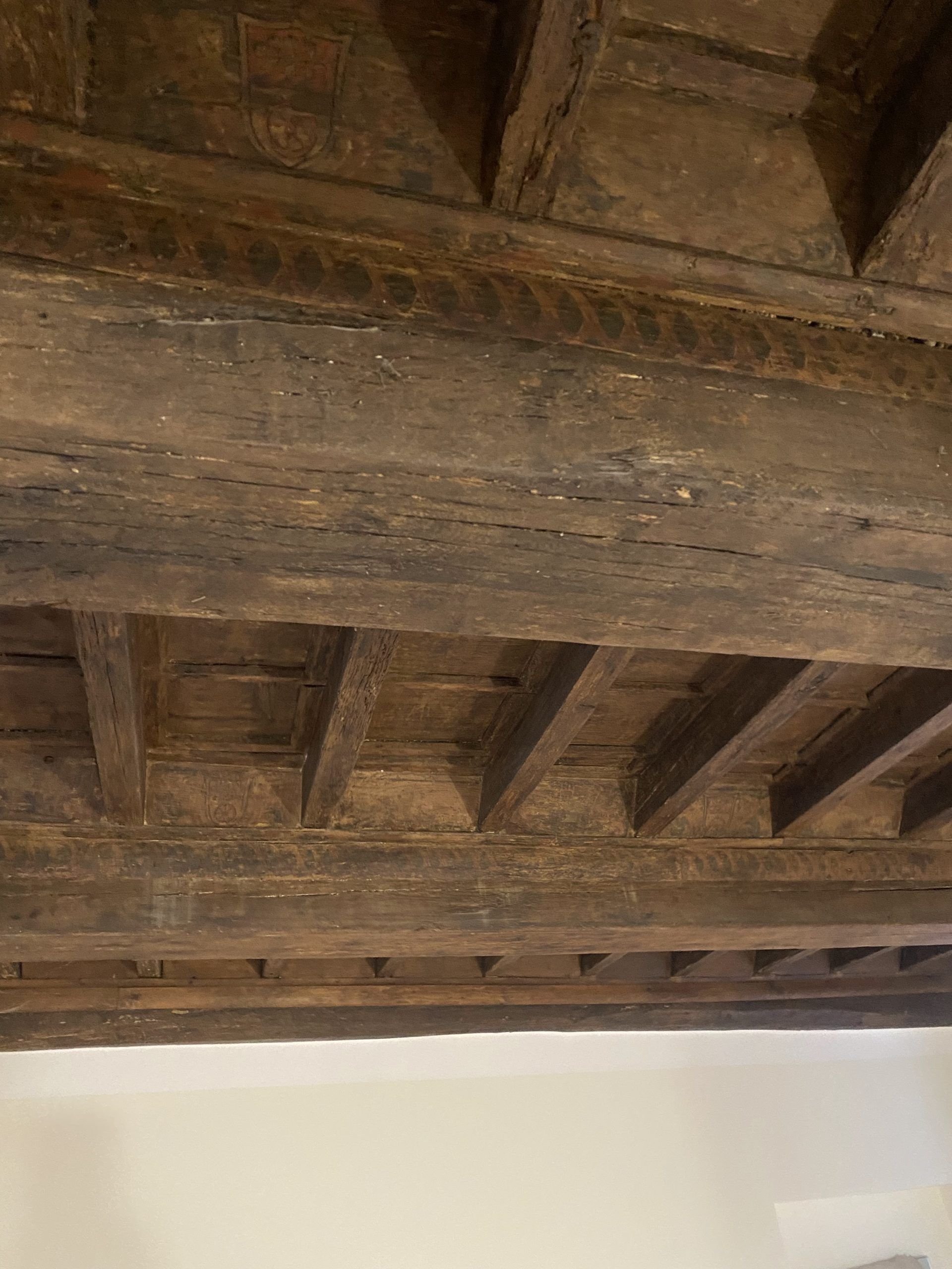 Travi in legno a vista sopra una parete bianca in un interno rustico