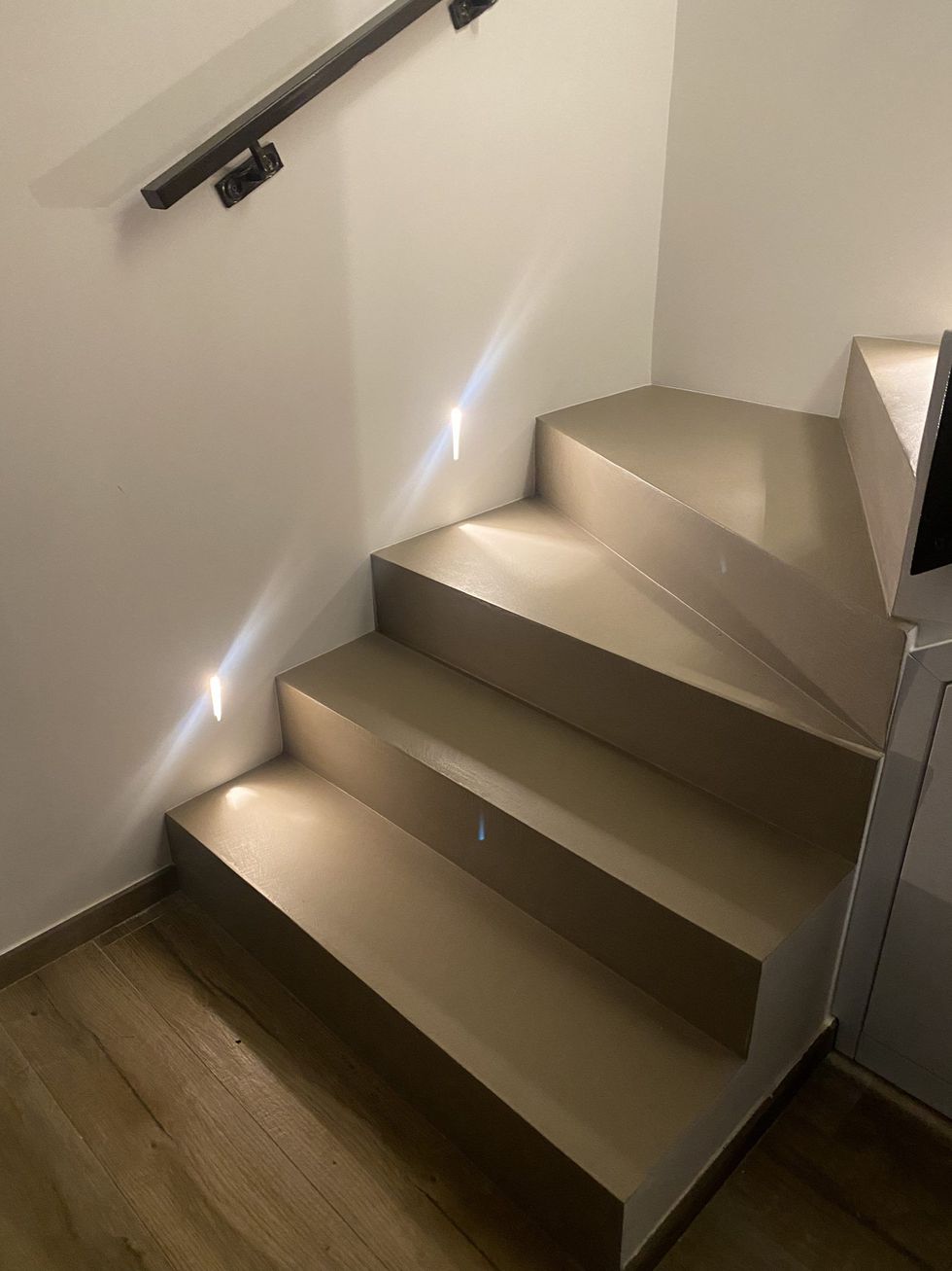 Bagno moderno con specchio a parete, mobile lavabo bianco e WC su pavimento in legno.
