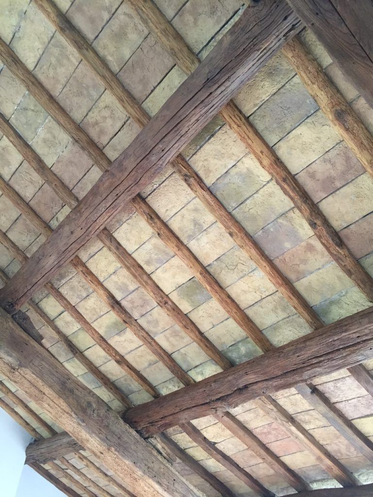 Trave in legno e soffitto in mattoni visti dal basso con travi trasversali diagonali