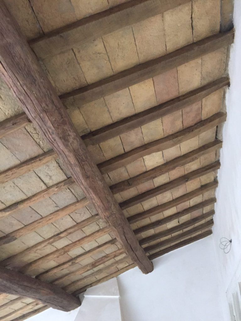 Trave in legno e soffitto piastrellato visti dal basso in una stanza bianca