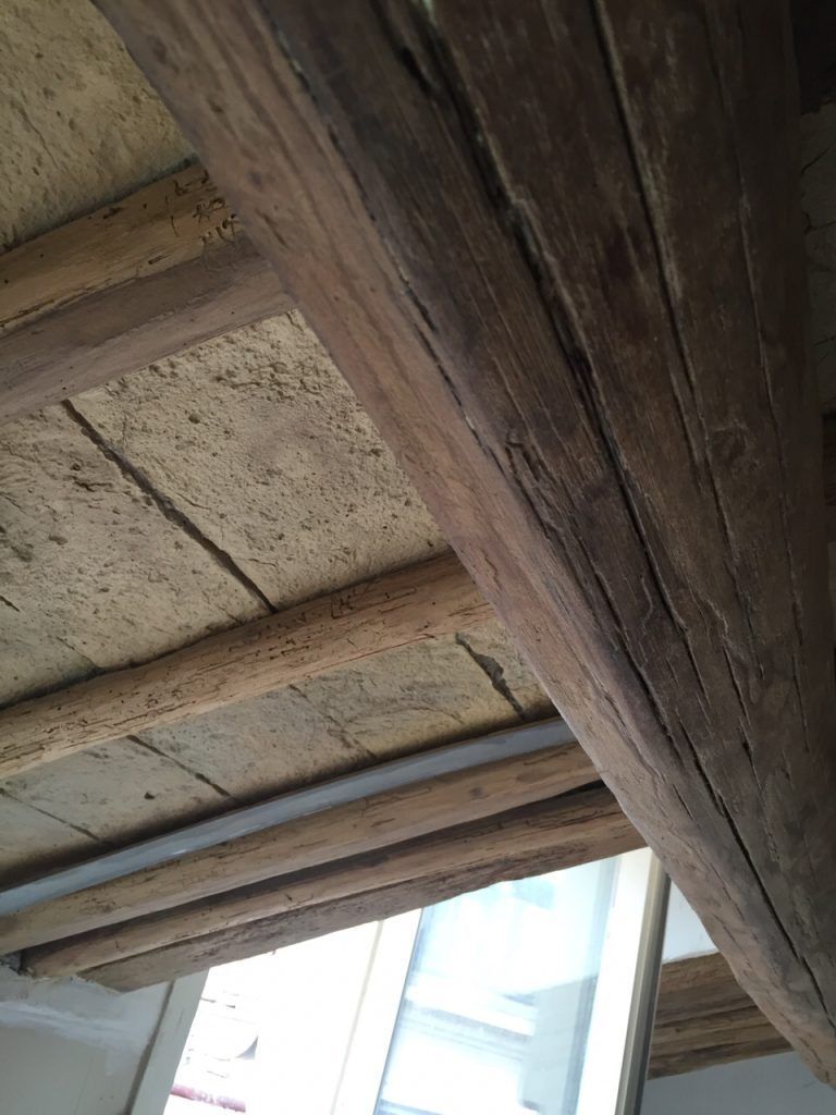 Travi in legno e pannelli del soffitto consumati dal tempo sopra una luminosa apertura verso il cielo