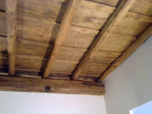 Travi e assi di legno sul soffitto sopra una parete bianca all'interno