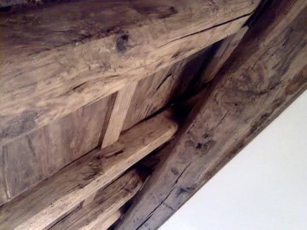 Primo piano di travi e assi di legno consumate dal tempo su uno sfondo bianco.