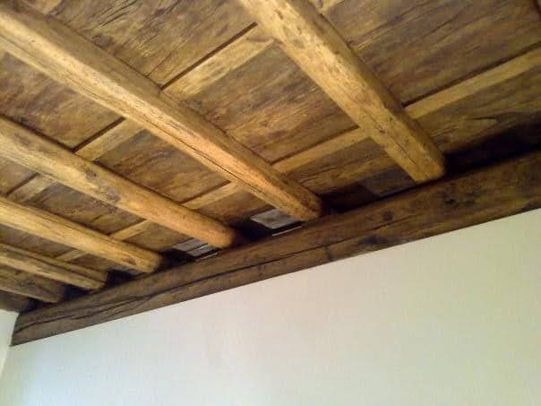 Soffitto con travi in legno e assi rustiche sopra una parete bianca