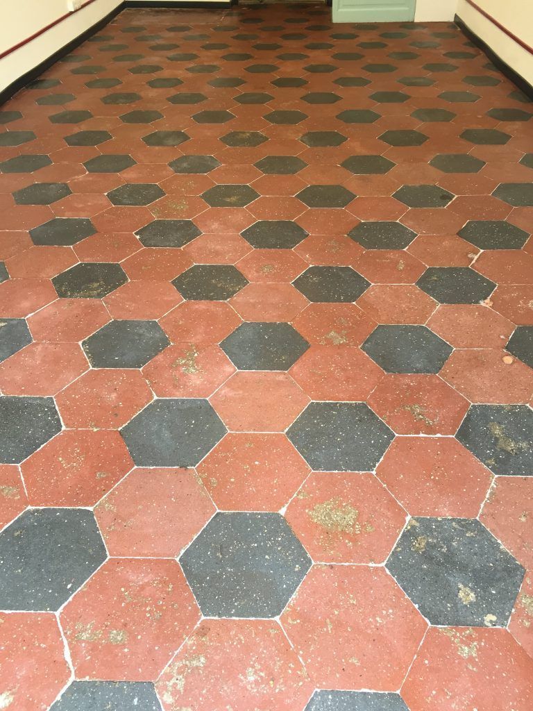 Pavimento in piastrelle esagonali rosse e nere in un corridoio, visto dall'alto.