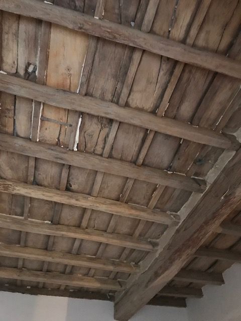 Soffitto in assi di legno con travi a vista, visto dal basso.