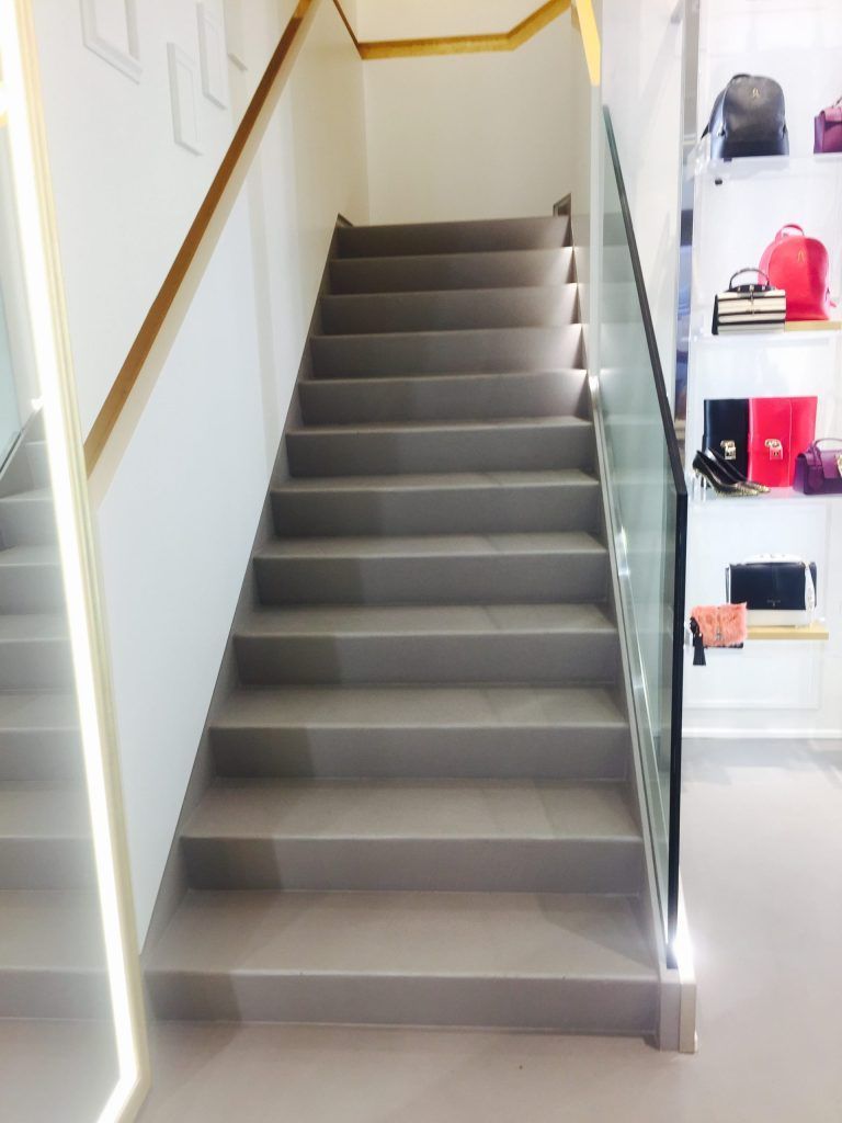 Scala interna con gradini rivestiti di moquette grigia e pareti bianche, vista dal basso.