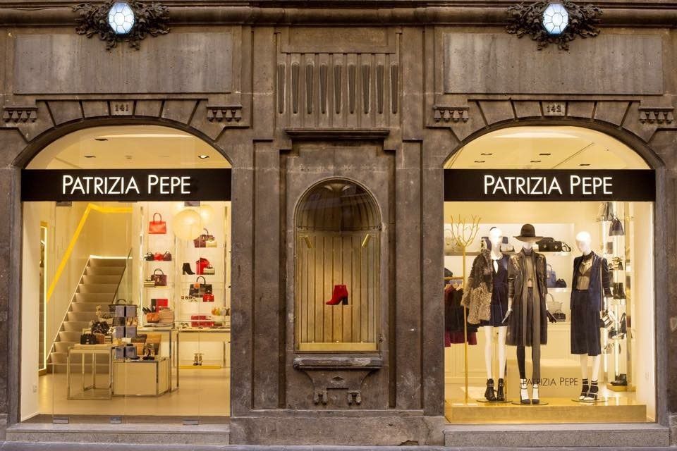 Vetrina del negozio Patrizia Pepe con due vetrine illuminate e ingresso centrale in pietra.