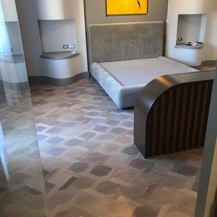 Camera da letto moderna con letto grigio, divisorio in legno curvato e nicchie a muro integrate.