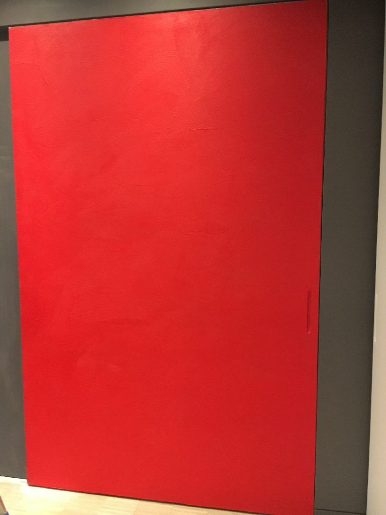 Porta rossa con cornice grigio scuro su una parete chiara