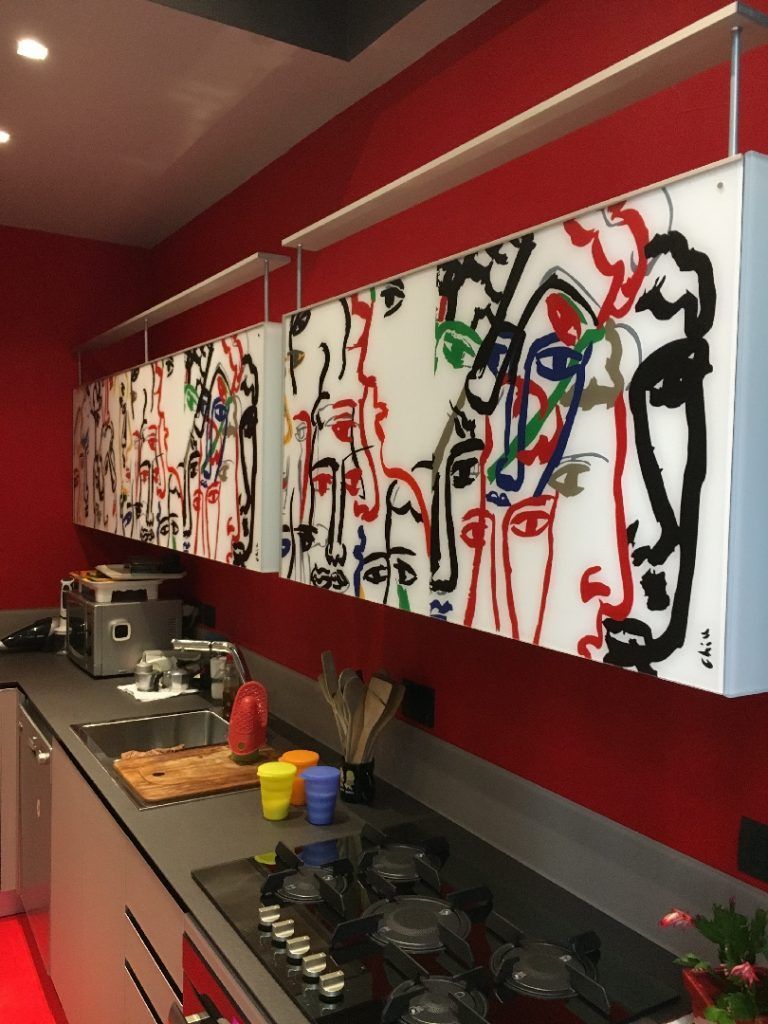 Cucina moderna con pareti rosse e quadro astratto colorato sopra il bancone.