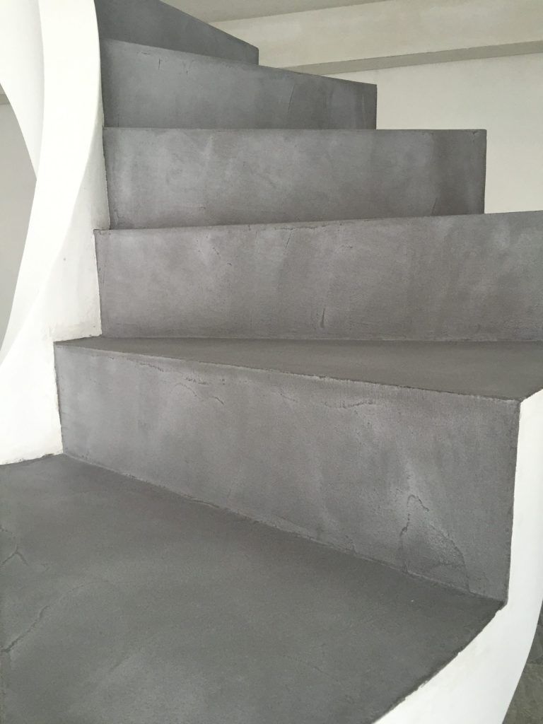 Scala in cemento grigio con pareti bianche e pavimento grigio scuro.