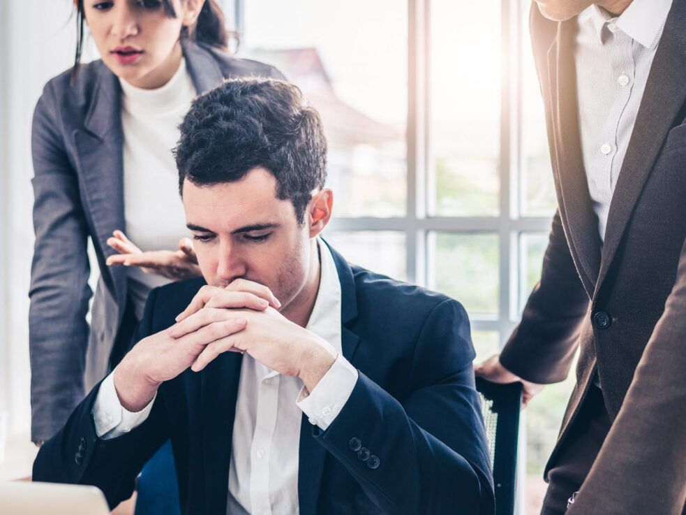 A group of business people are looking at a laptop computer.