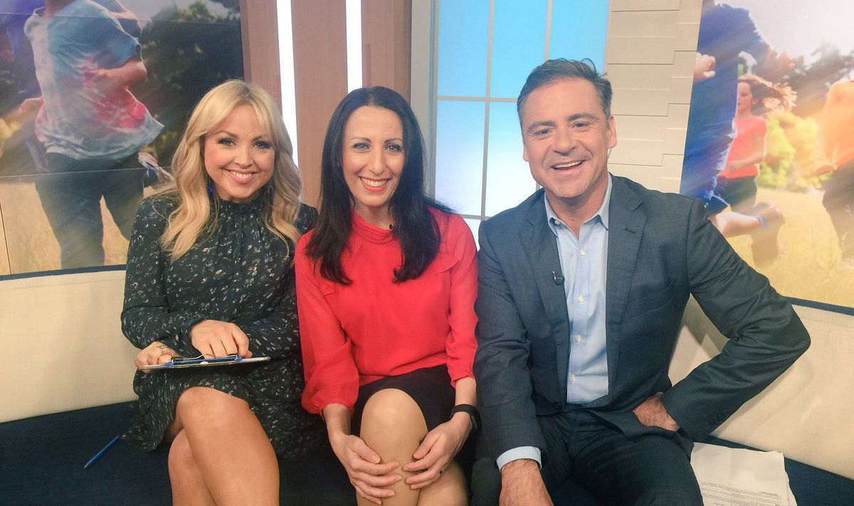 A man in a suit and two women are sitting on a couch.