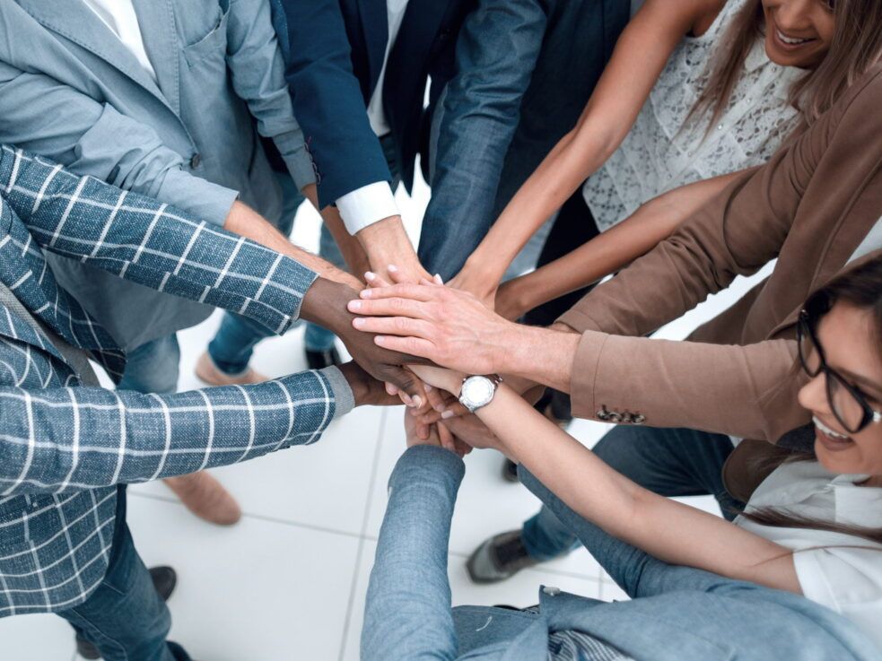 A group of people are putting their hands together in a huddle.