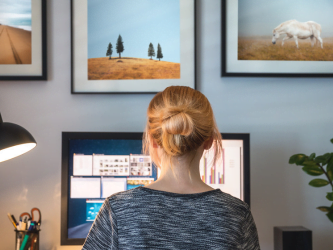 A woman is sitting at a desk looking at a computer screen.
