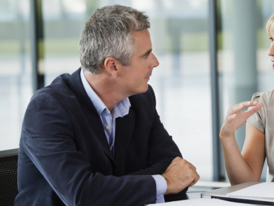 A man and a woman are sitting at a table talking to each other