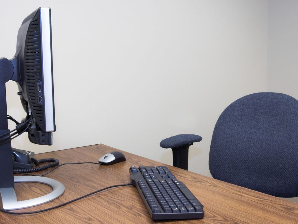 A computer monitor sits on a desk next to a keyboard and mouse