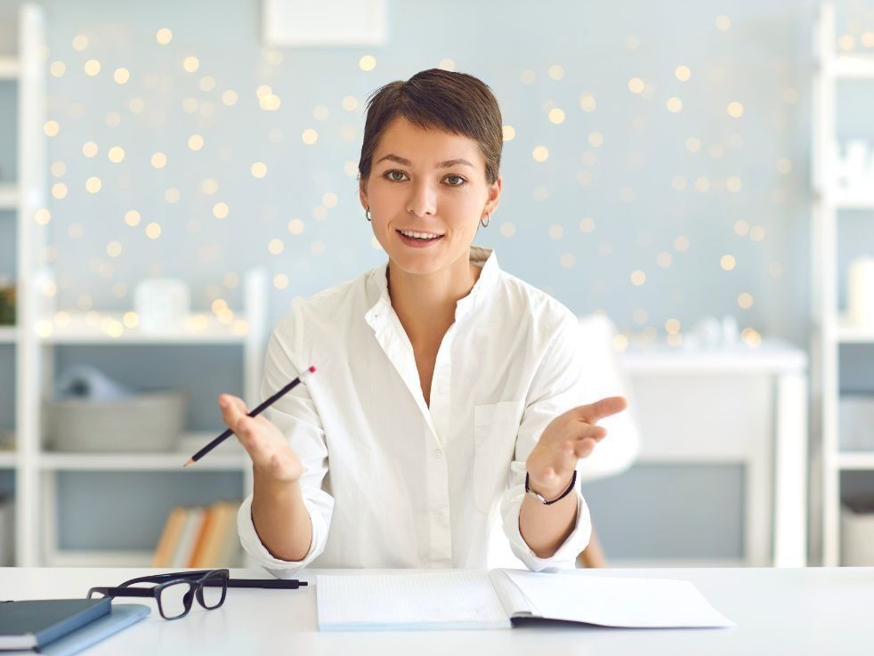 A woman is sitting at a desk with a pen in her hand.