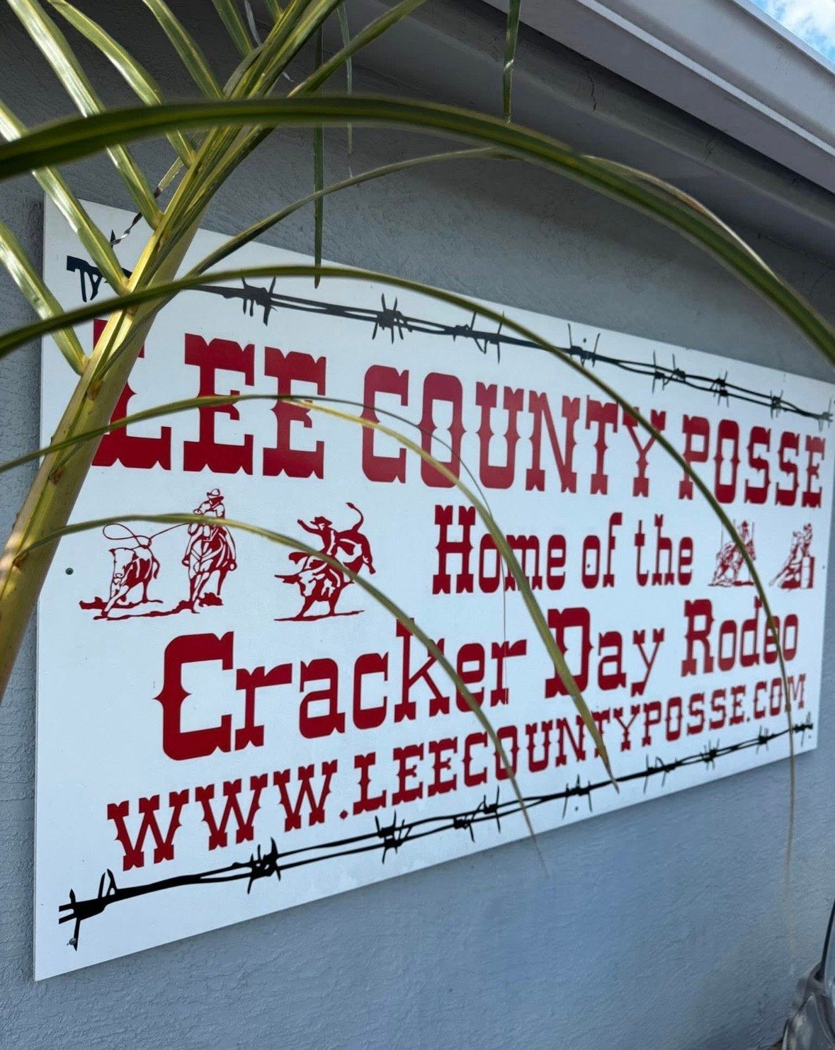 Lee County Posse sign for the Cracker Day Rodeo, red text on a white wall.