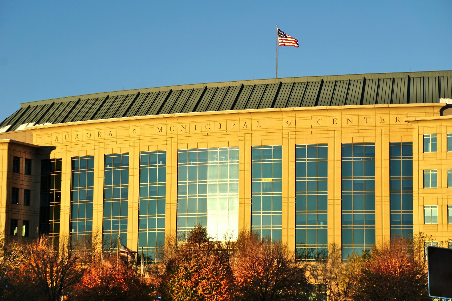 Large building with reflective windows and American flag on top.