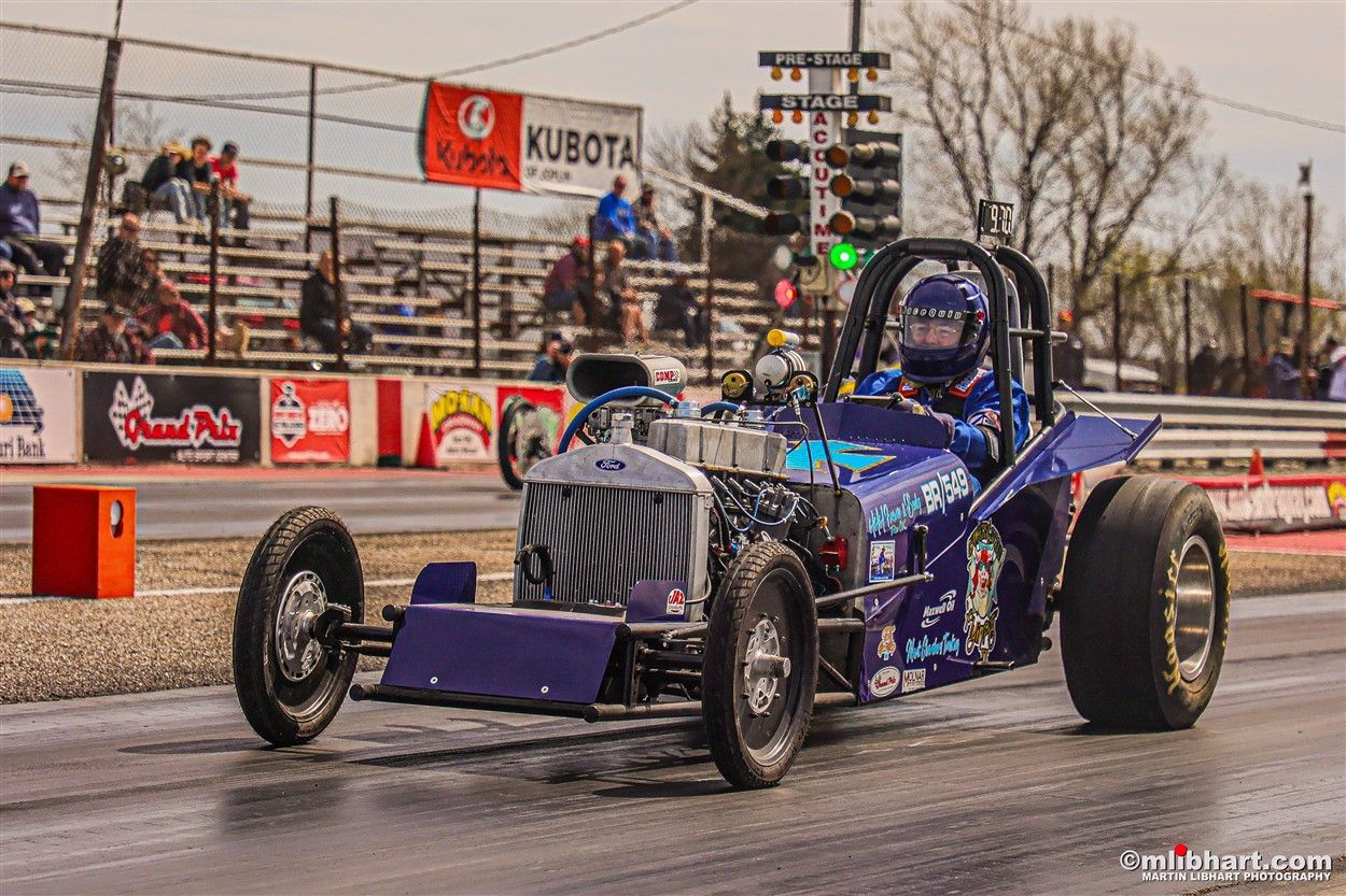 A purple race car is driving down a race track.