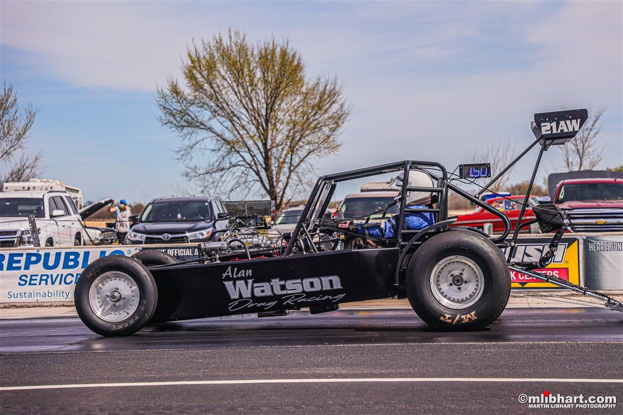 A black race car is parked on the side of the road.