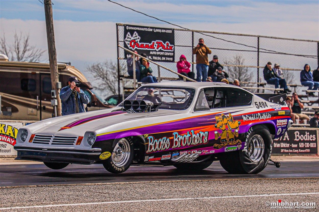 A purple and white race car is driving down a track.