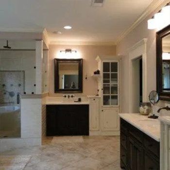 Spacious bathroom with shower, vanity, and storage cabinet. Features dark wood accents, light walls, and marble flooring.