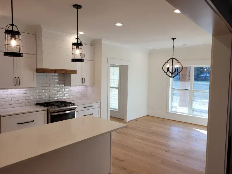 Modern kitchen with white cabinets, subway tile, stainless steel appliances, and wooden floors.