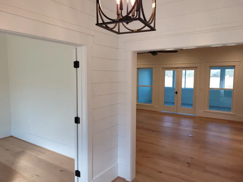 Interior view of a room with light wood floors, white walls, and a decorative black chandelier.