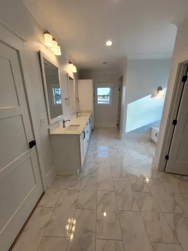 Spacious white bathroom with marble tile floor, double vanity, and natural light.