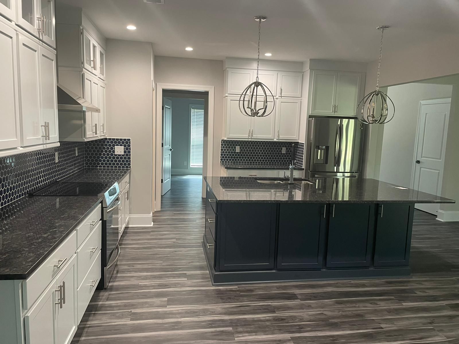 Modern kitchen with gray cabinets, dark countertops, island, and stainless steel appliances.