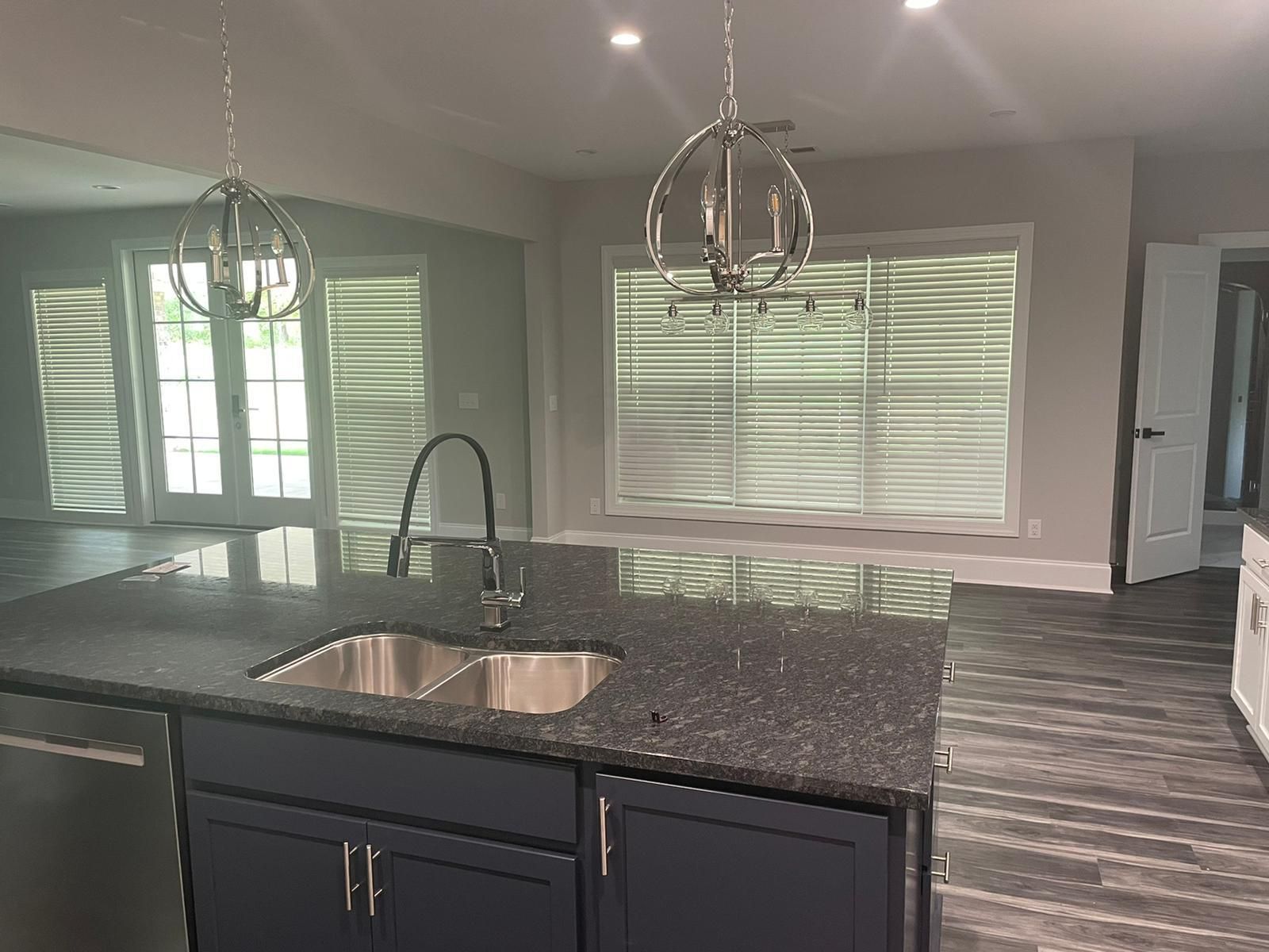 Modern kitchen with island, granite countertop, sink, blue cabinets, and pendant lights.