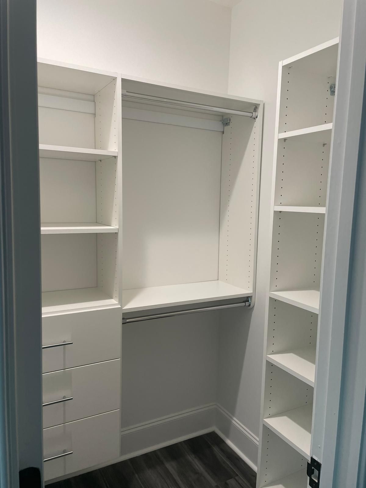White closet with shelves, drawers, and hanging rods; empty.