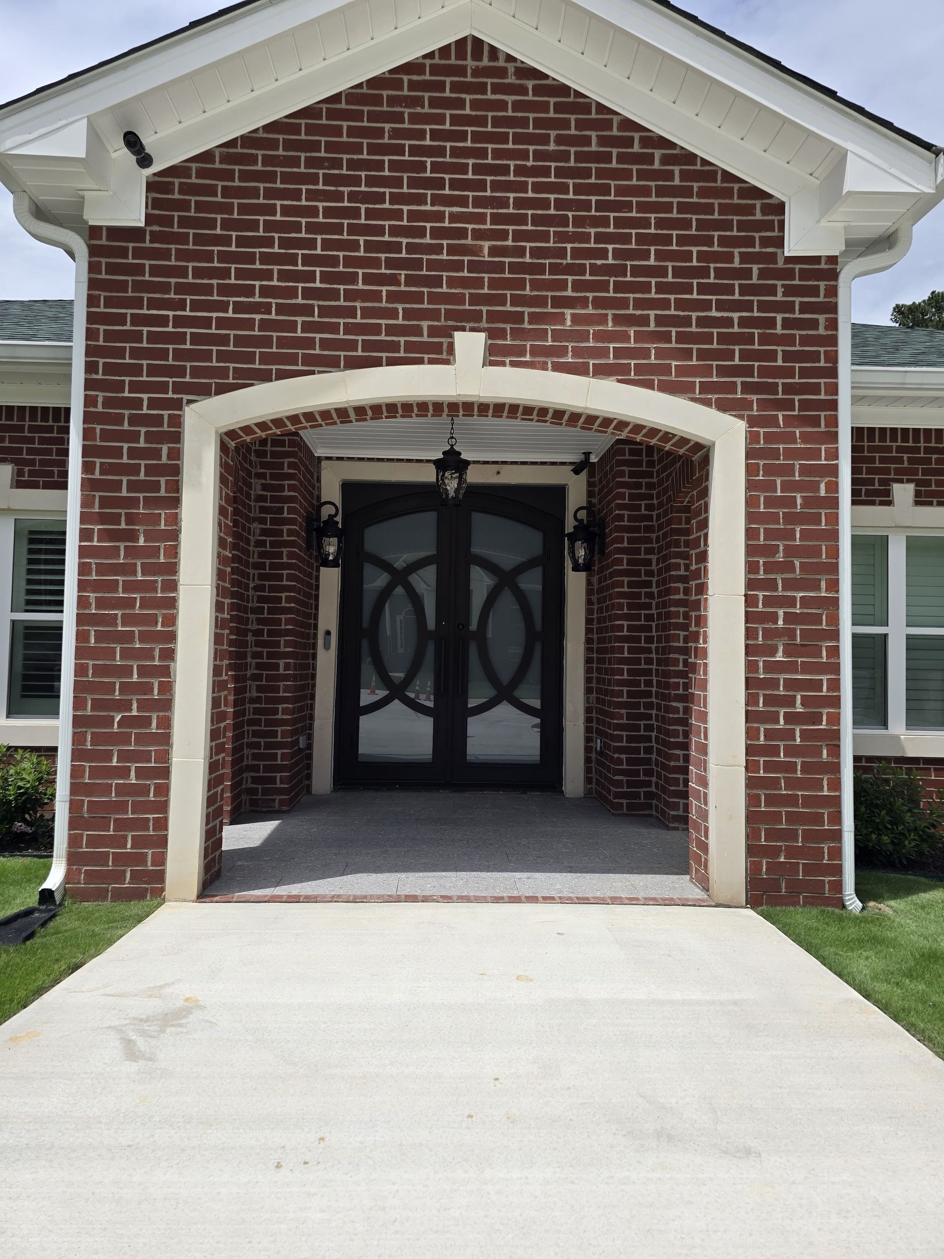 Red brick home entrance with double doors framed by white trim and an arched entryway.