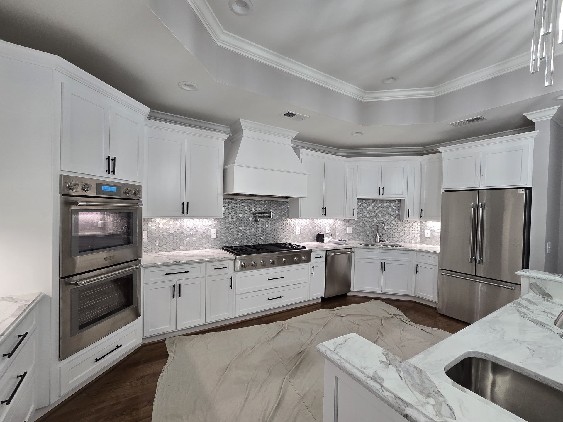 White kitchen with stainless steel appliances, marble countertops, and white cabinets.