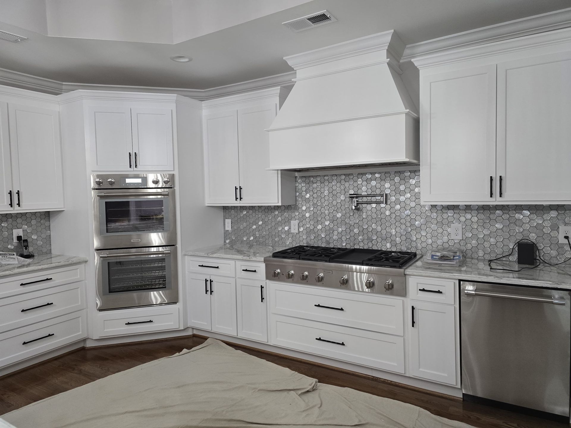 White kitchen with stainless steel appliances and gray tile backsplash.