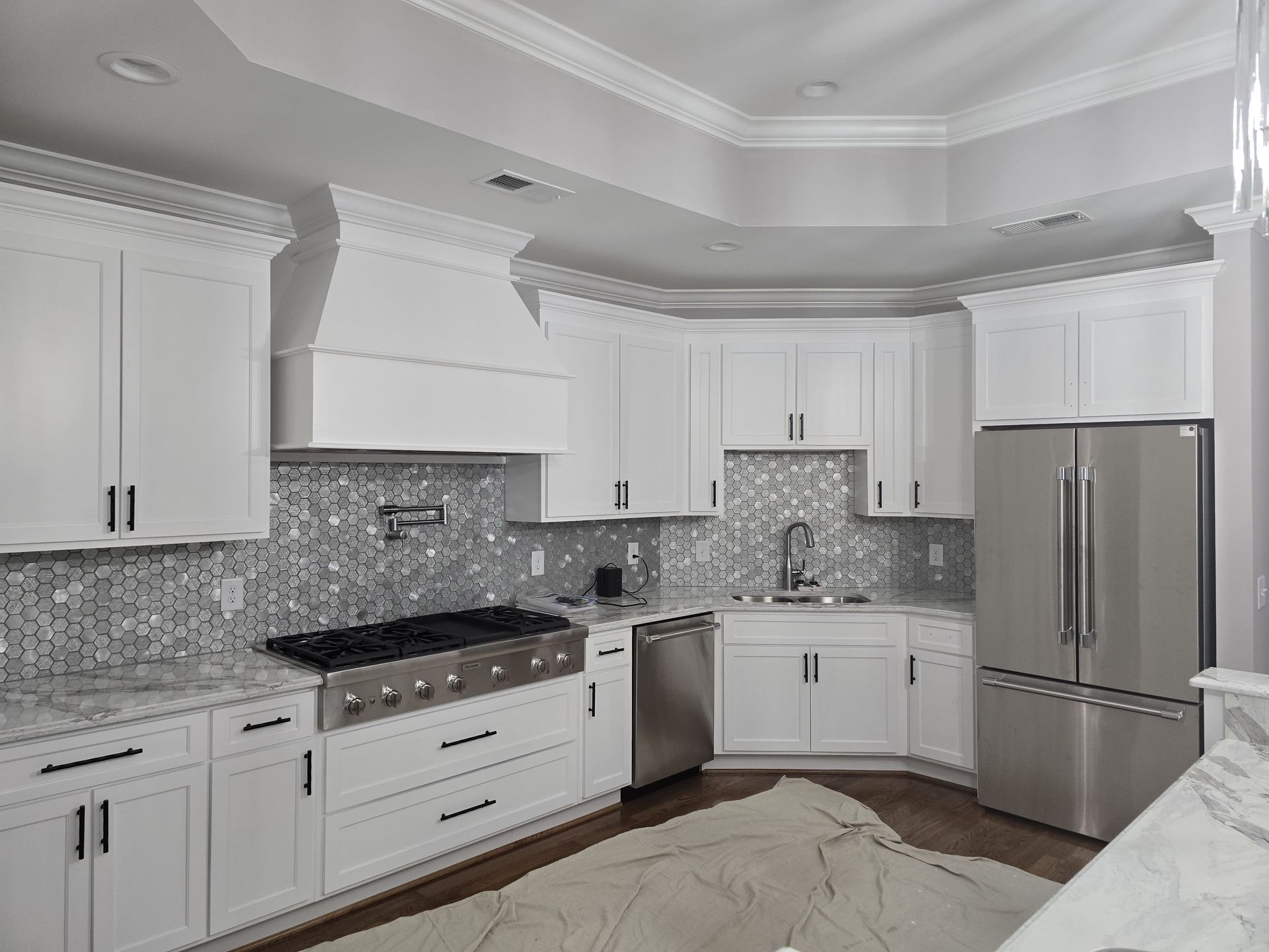White kitchen cabinets with stainless steel appliances and backsplash.