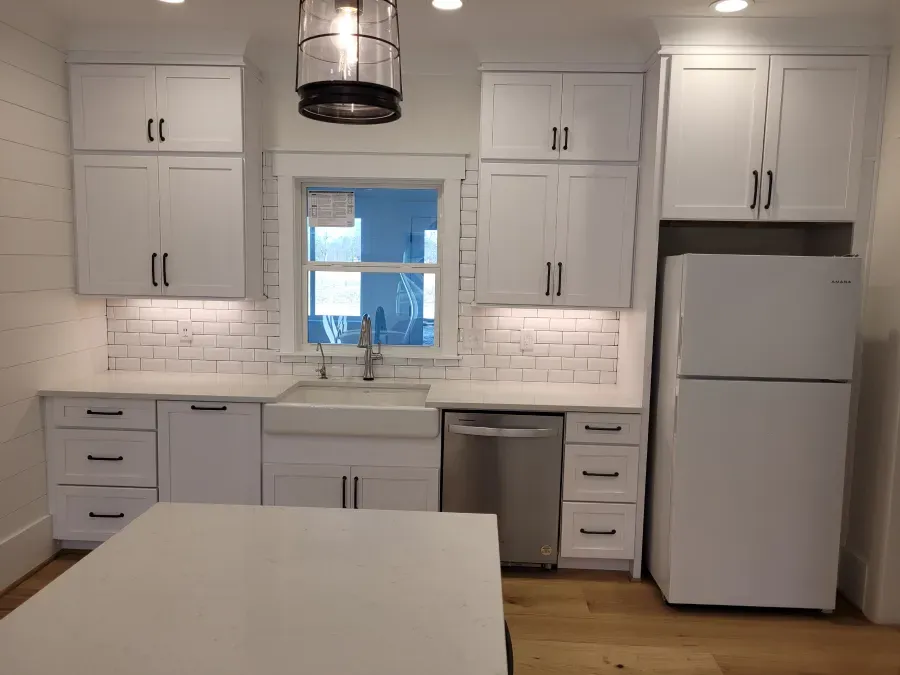 White kitchen with cabinets, a window, stainless steel appliances, and an island.