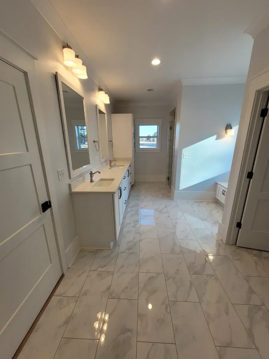 Spacious white bathroom with dual vanities, marble floors, and natural light.