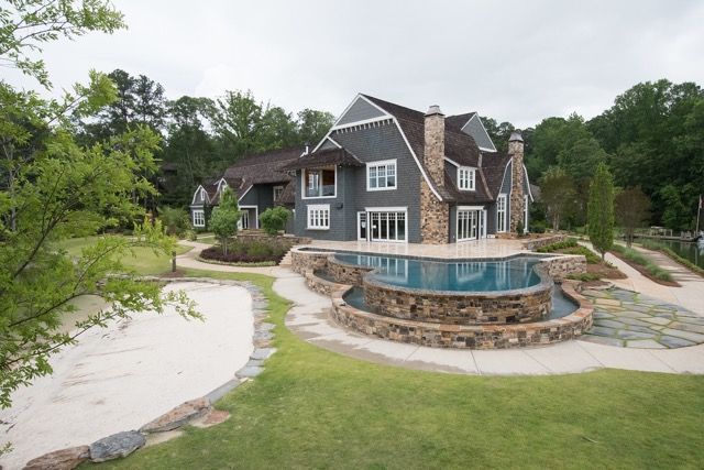 Gray house with pool, landscaping, and stone accents.