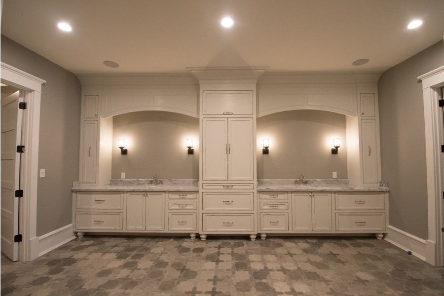 Built-in white cabinets with arched alcoves and lights, gray walls, tile floor.
