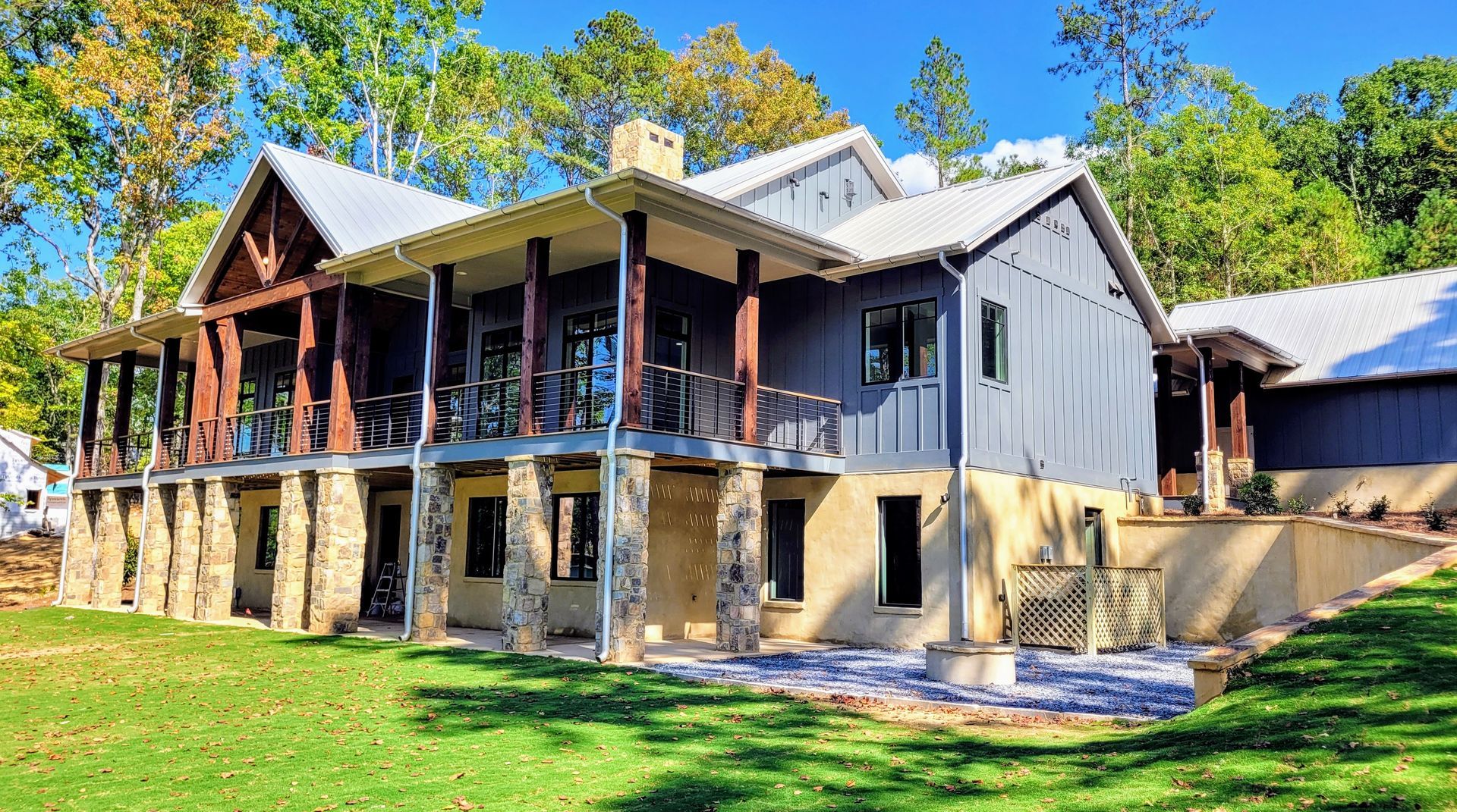 Two-story house with a covered porch and stone foundation, set on a grassy lawn.