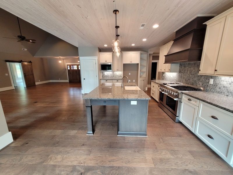 Spacious kitchen with wood floors, island, stainless steel appliances.