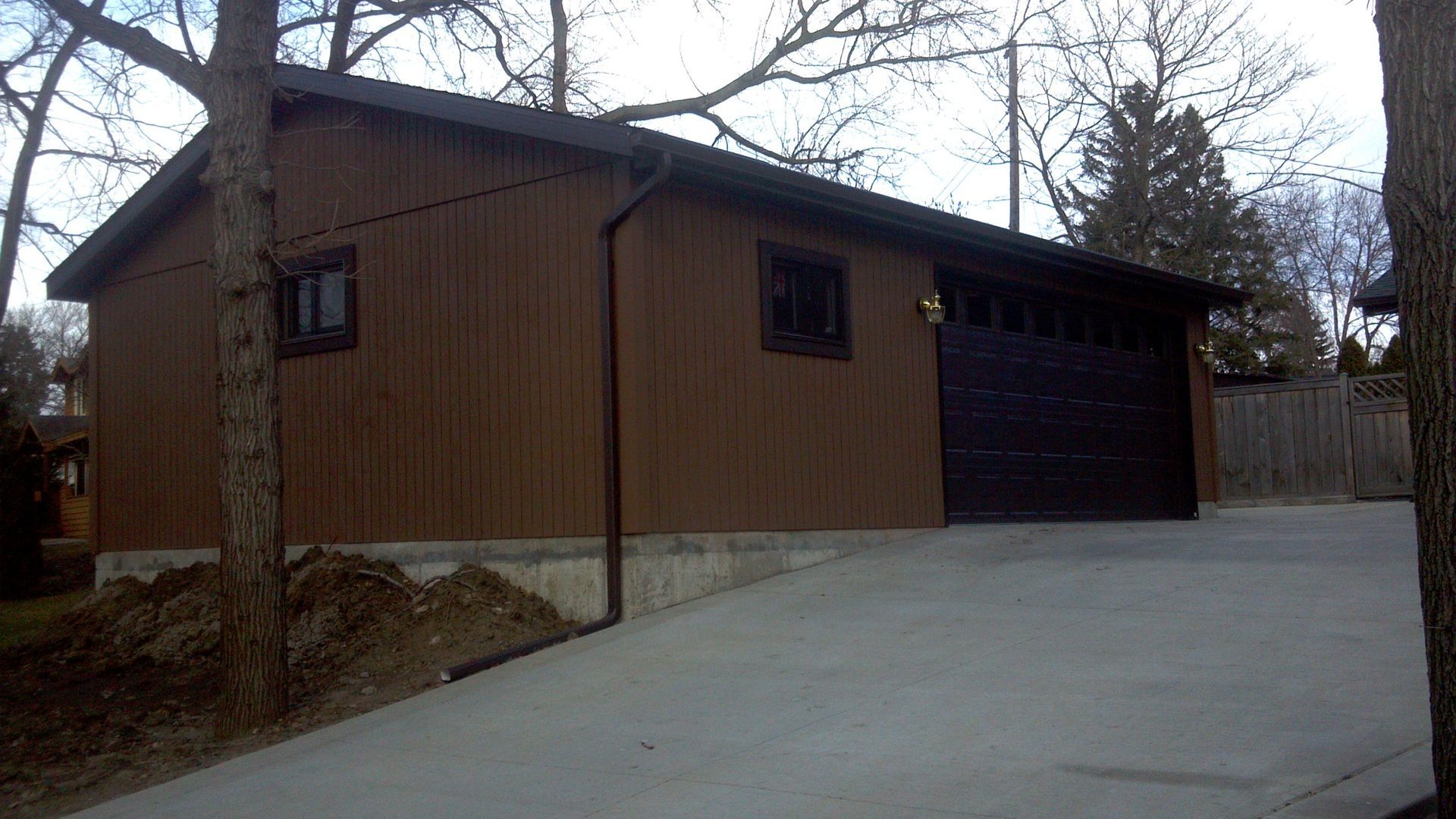 A brown garage with a black garage door and a concrete driveway.