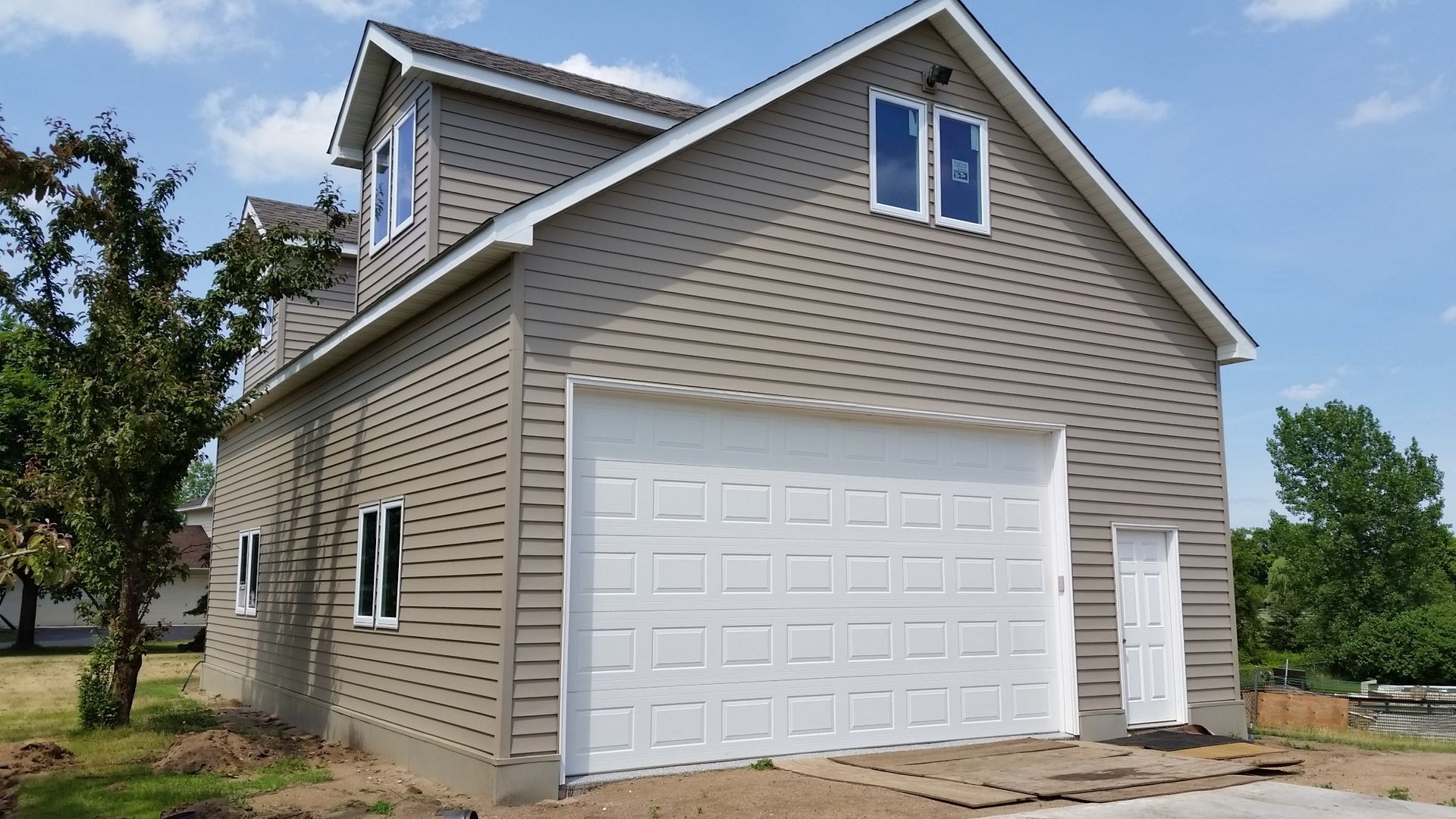 A house with a white garage door and a blue sky in the background