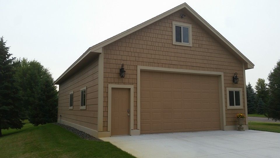 A brown garage with two garage doors and a driveway